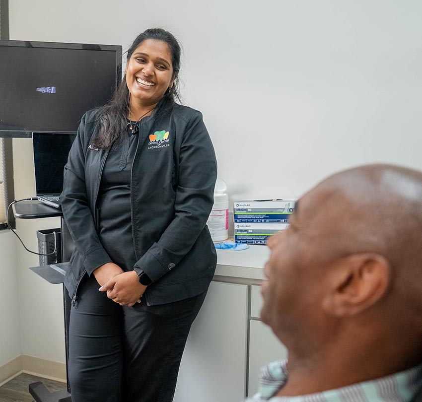 female dental staff member of the Dental Center of Jacksonville, FL smiles to a patient