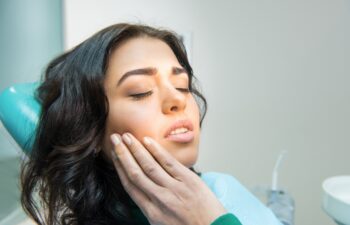 Young woman having toothache. Sad lady at the dentist. Gum disease symptom.