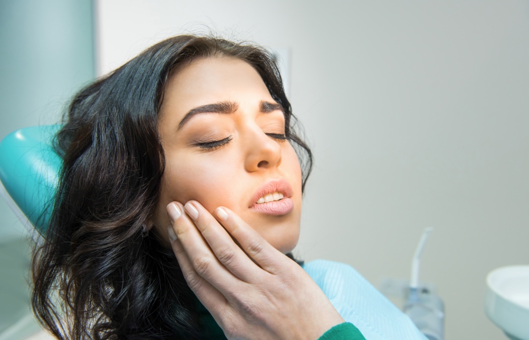 Young woman having toothache. Sad lady at the dentist. Gum disease symptom.