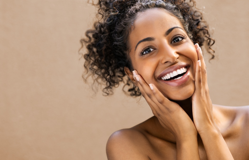 Beautiful young woman smiling after fantastic face treatment. Happy beauty african girl excited after spa treatment isolated on background with copy space. Surpise and astonishment beauty concept.