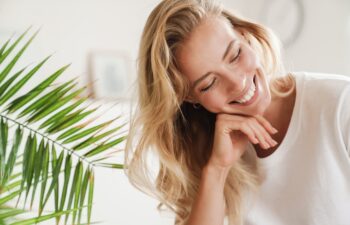 Smiling young beautiful blonde woman wearing t-shirt standing at the living room