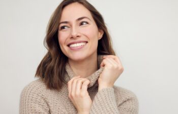 Portrait of young happy woman smiling on white background while looking left. Big smile on her face, looking beautiful, natural and charming.