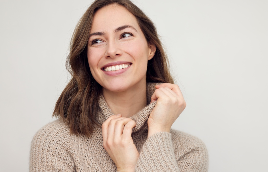 Portrait of young happy woman smiling on white background while looking left. Big smile on her face, looking beautiful, natural and charming.