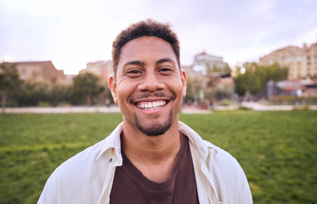 Handsome happy African American bearded man. Portrait of cheerful young man standing outdoors and smiling at camera. Positive emotion concept of male person. Generation z guy look carefree and natural