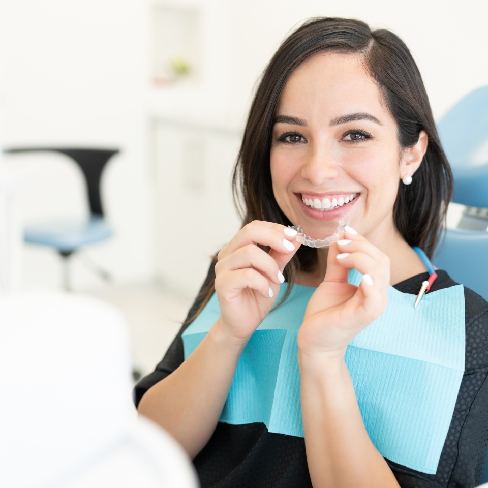 Smiling beautiful Caucasian mid adult woman holding invisible orthodontic retainer