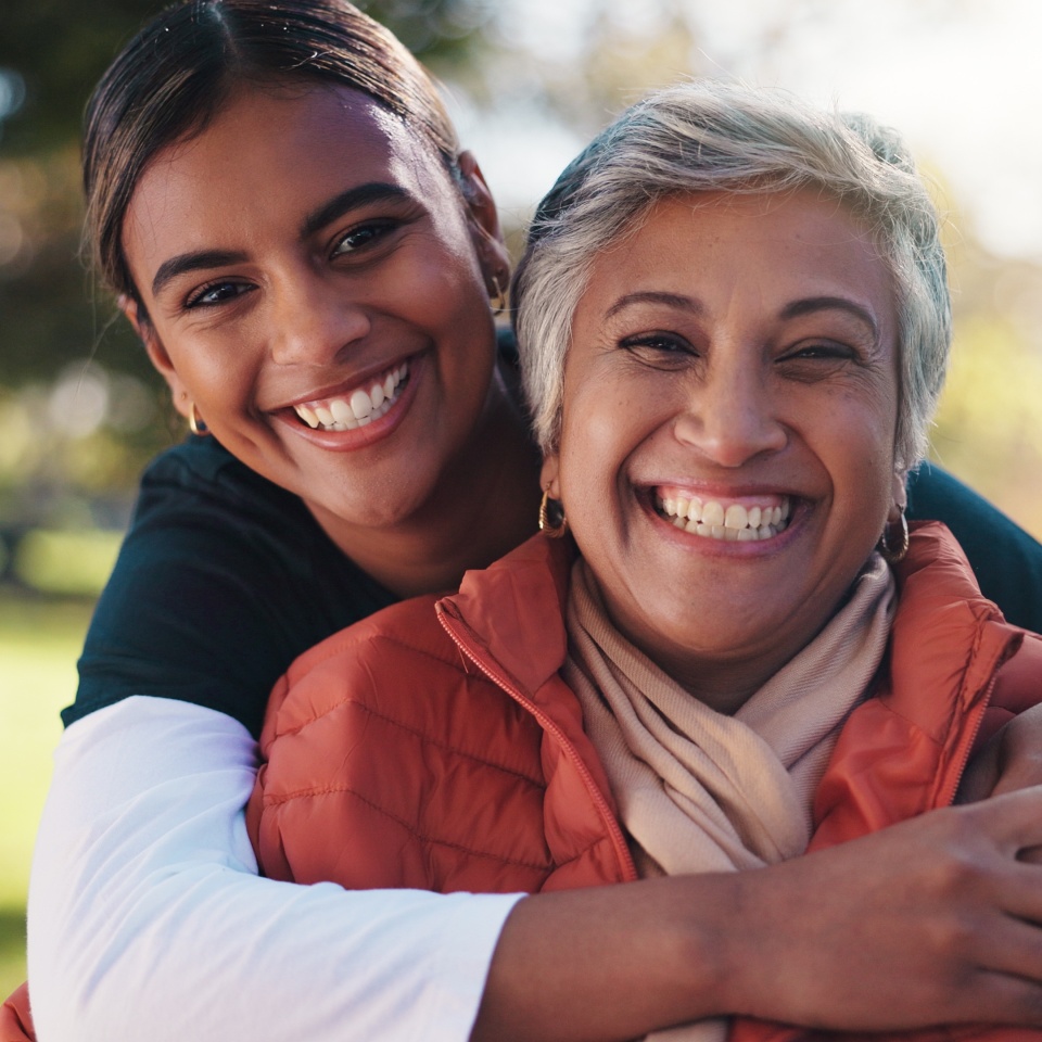 Hug, portrait and smile of caregiver with old woman in park for assisted living or rehabilitation. Love, support or wellness with happy nurse and senior patient embracing in nature for retirement